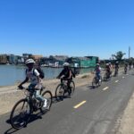 Kids riding bikes and smiling on the Sausalito bike path past floating homes