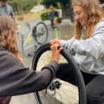 Two girls fixing a bike tire