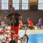Boy holding a bike up on one wheel in a gym