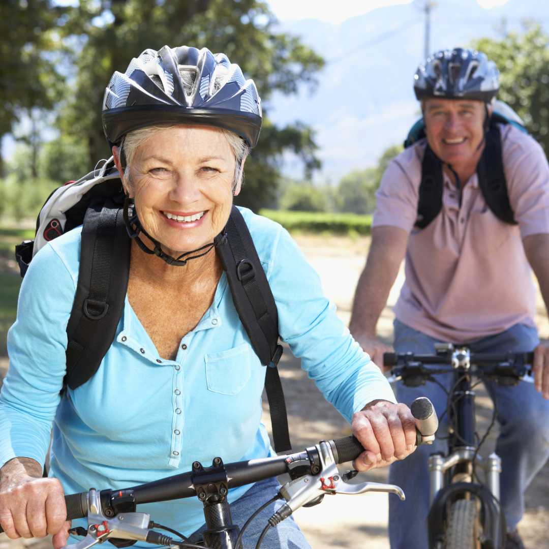 two older adults riding e-bikes on a pathway