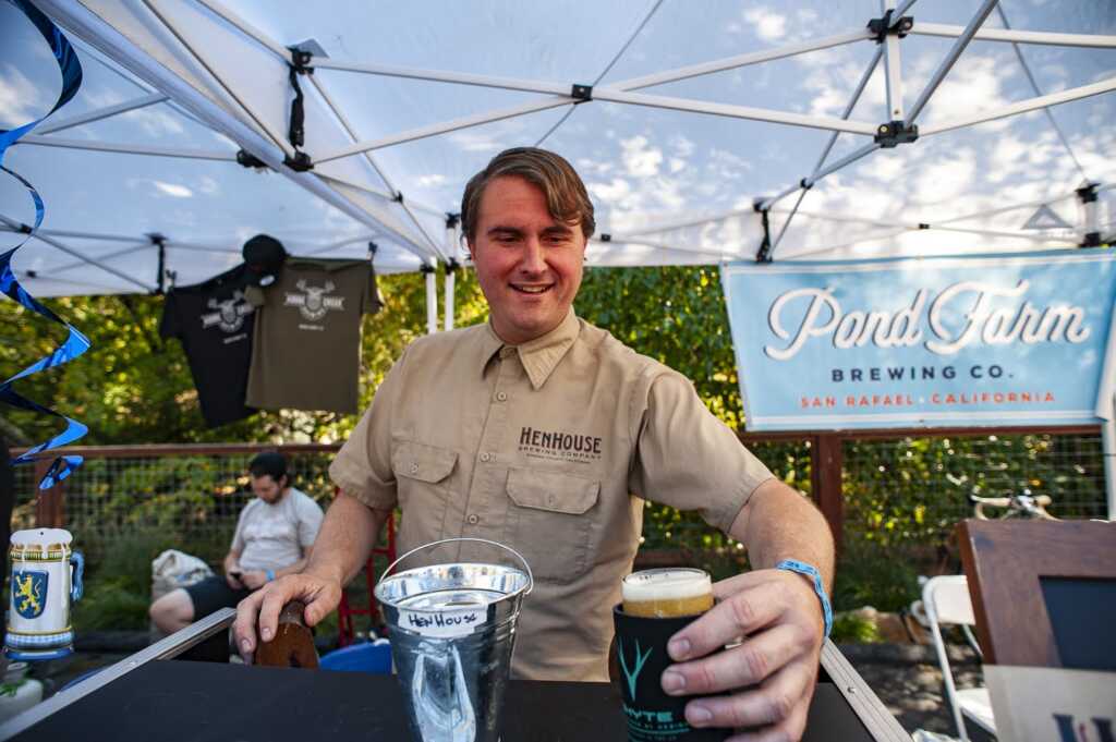 Guy serving a beer with Pond Farm sign in background Biketoberfest