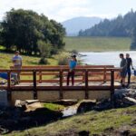 Volunteers building wooden bridge by reservoir in Marin Water watershed.