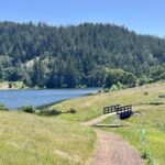 Wooden bridge on Liberty Gulch Trail with lake and forested hills in background.