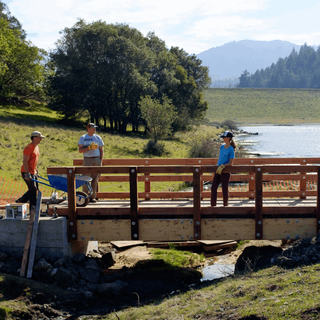 Volunteers building wooden bridge by reservoir in Marin Water watershed.