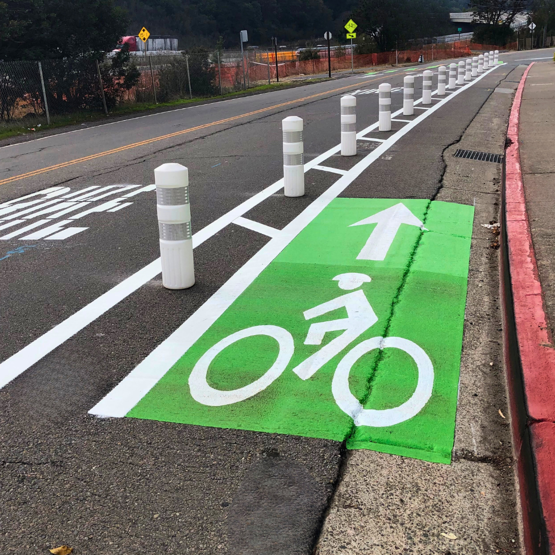 Protected bikeway with green painted pavement and white bike and arrow paint in San Rafael
