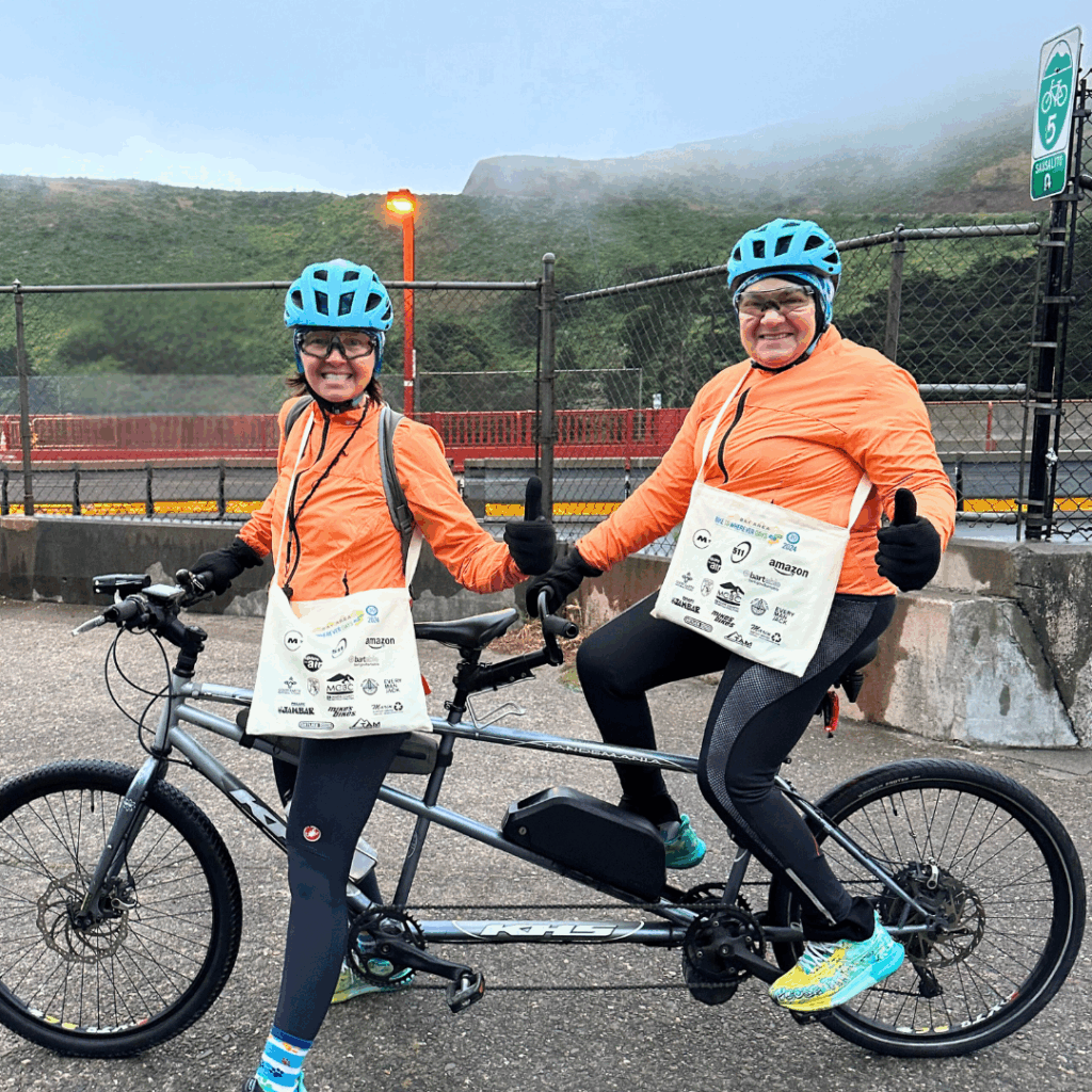 two women on a tandem bike with bike to work day bags at Golden Gate Bridge energizer station