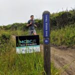 Runner passing MCBC Trail Stewards sign next to Dias Ridge Trail signpost