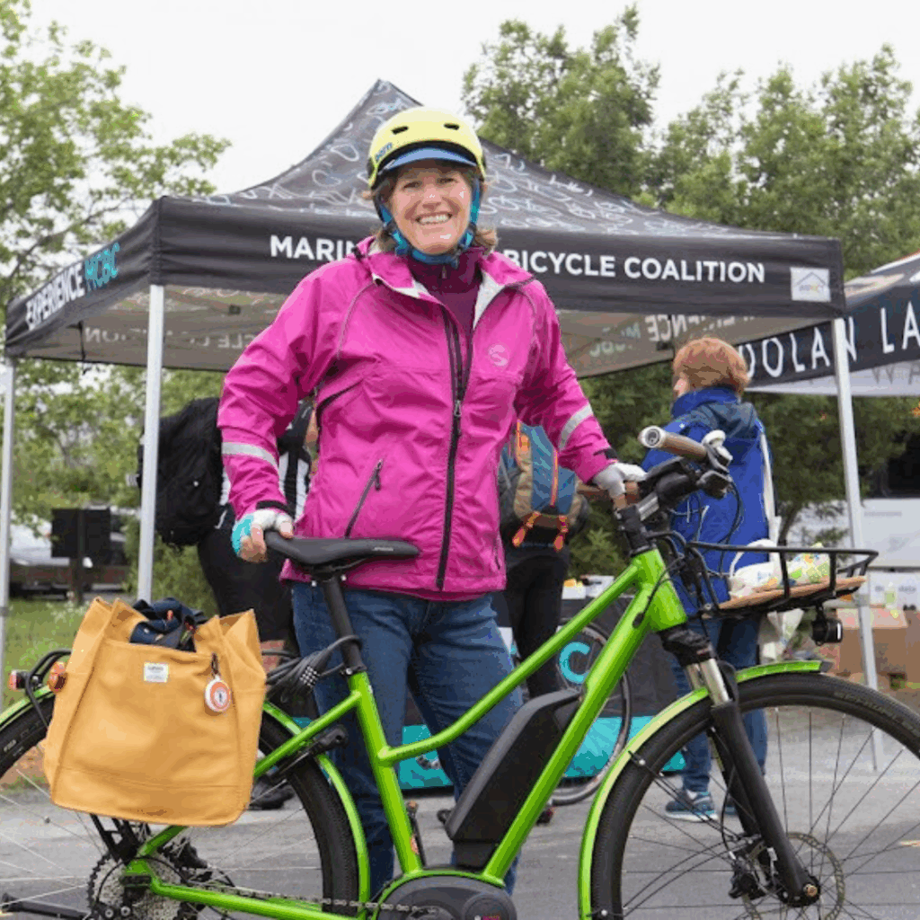 woman with pink jacket and green bike with an e-bike