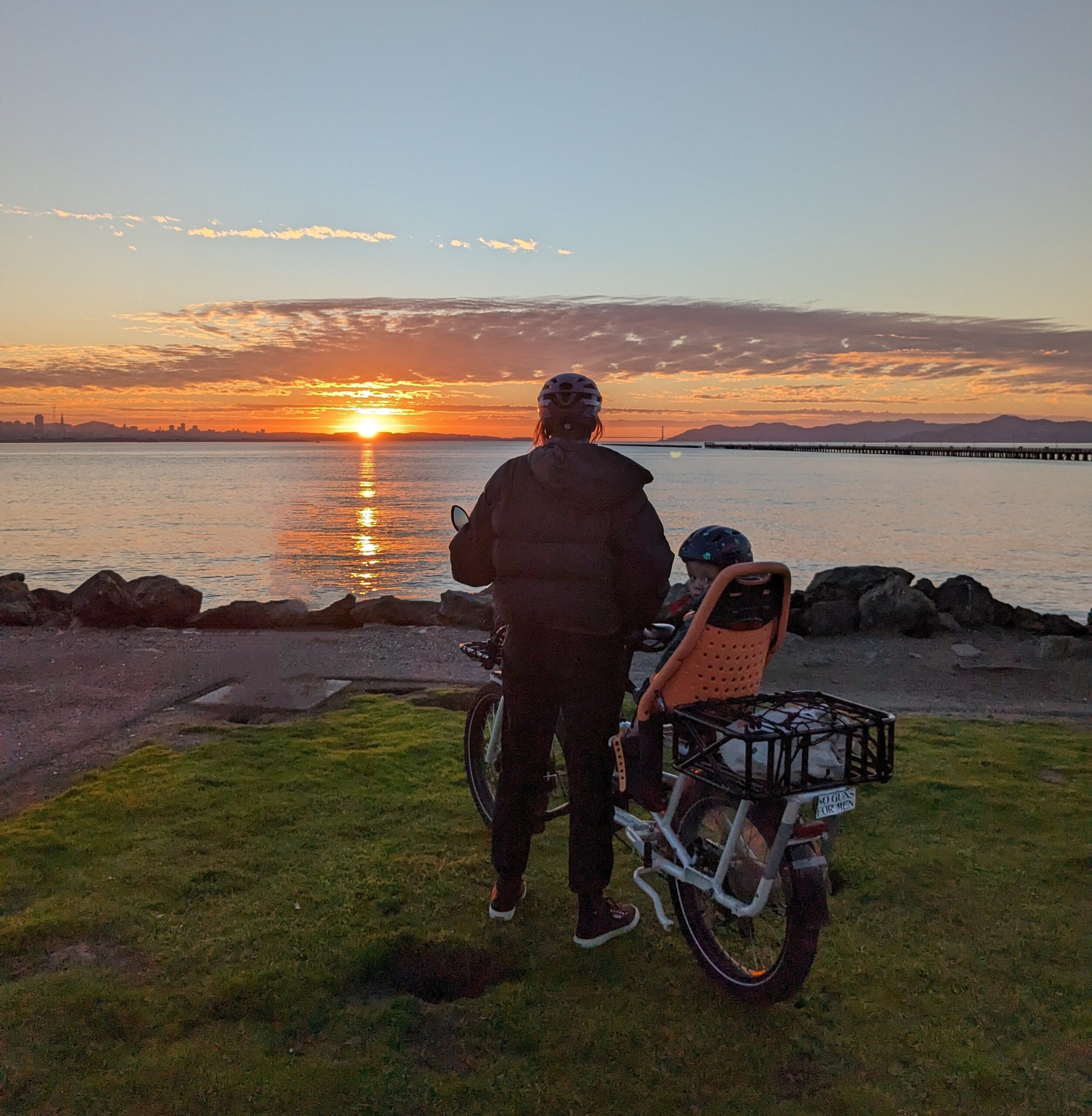 E-bike rider and child look at sunset over the Bay